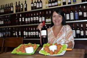 Maria José mostrando opções de petiscos e vinho para consumir no local. Foto: Ana Paula Bonelli