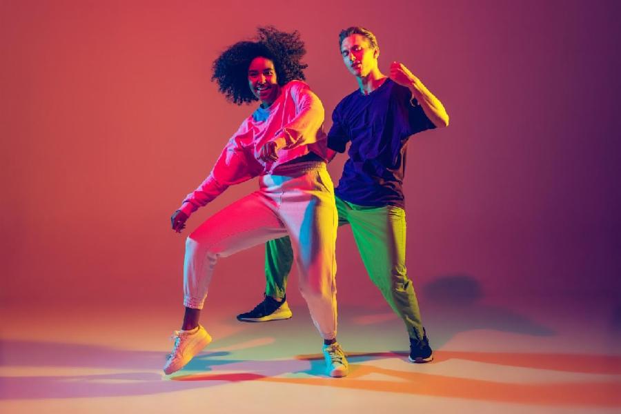 1624046201360-dance-time-stylish-men-and-woman-dancing-hip-hop-in-bright-clothes-on-green-background-at-dance-hall-in-neon-light
