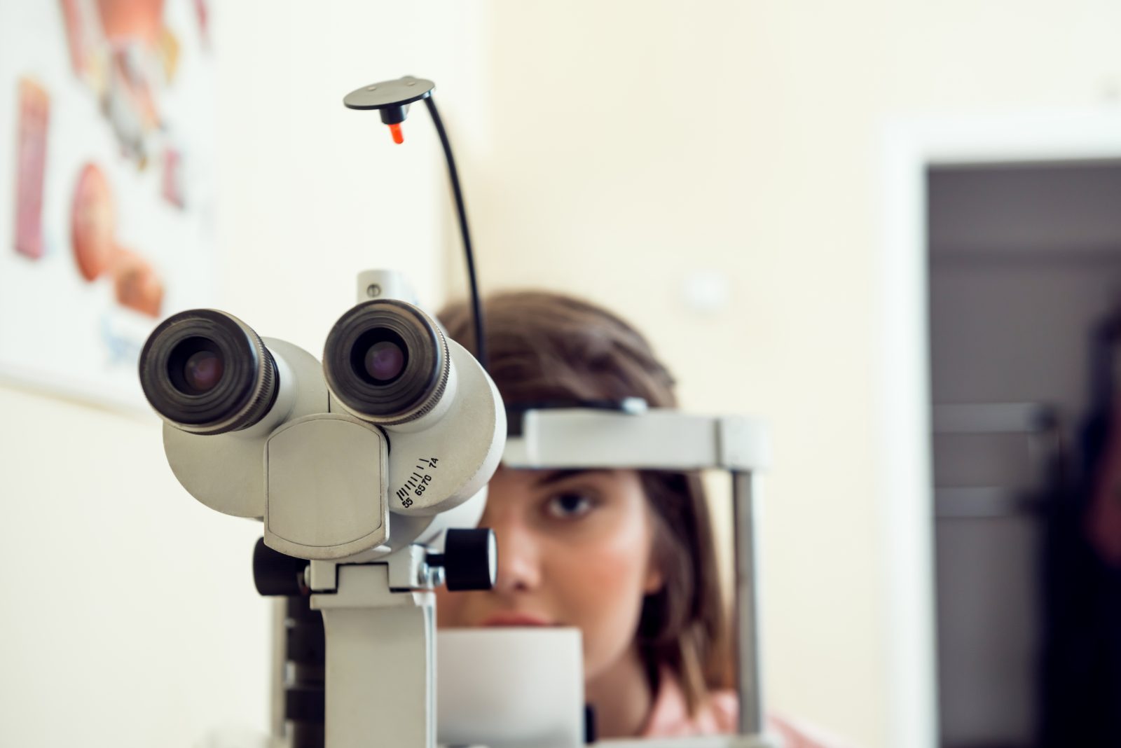portrait-of-cute-caucasian-female-patient-sitting-in-optometrist-office-waiting-for-start-of-procedure-to-check-her-vision-with-microbioscope-sitting-over-yellow-wall-ophthalmology-concept