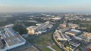 Vista aérea da economia da Serra com galpões logísticos e complexo industrial ao redor de rodovia.