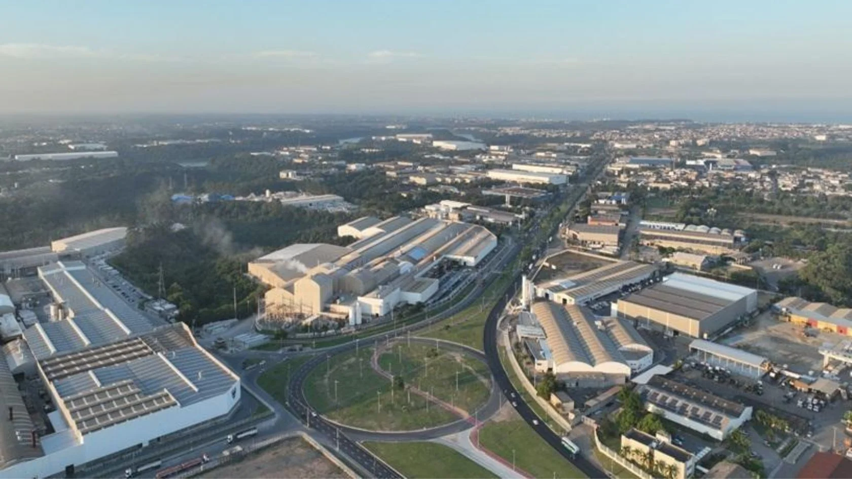Vista aérea da economia da Serra com galpões logísticos e complexo industrial ao redor de rodovia.