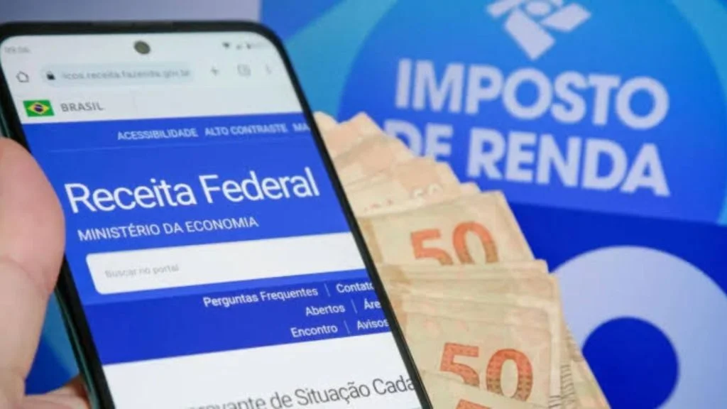 Celular com site da Receita Federal e notas de dinheiro ilustram restituição do Imposto de Renda