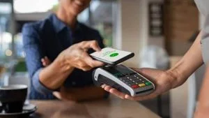 Cliente aproxima o celular da maquininha para pagar com Pix por aproximação em cafeteria