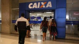 Pessoas entram em agência da Caixa Econômica Federal, responsável pelas novas regras do saque-aniversário FGTS