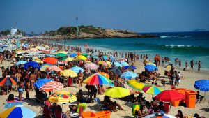 Praia lotada de banhistas e guarda-sóis coloridos no feriado de 12 de outubro