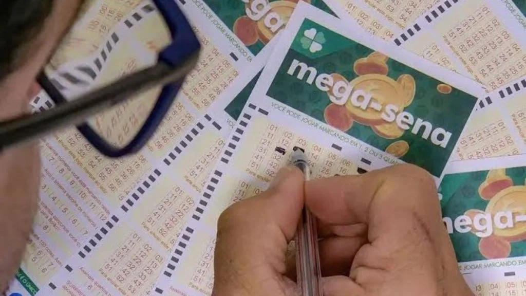 Pessoa de óculos marca números com caneta em volante da Mega-Sena, que está acumulada em R$ 52 milhões