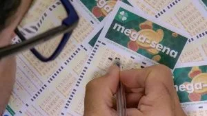 Pessoa de óculos marca números com caneta em volante da Mega-Sena, que está acumulada em R$ 52 milhões