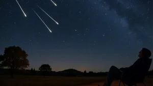 Pessoa em cadeira reclinável observa meteoros riscando o céu estrelado, ilustrando a chuva de meteoros em outubro