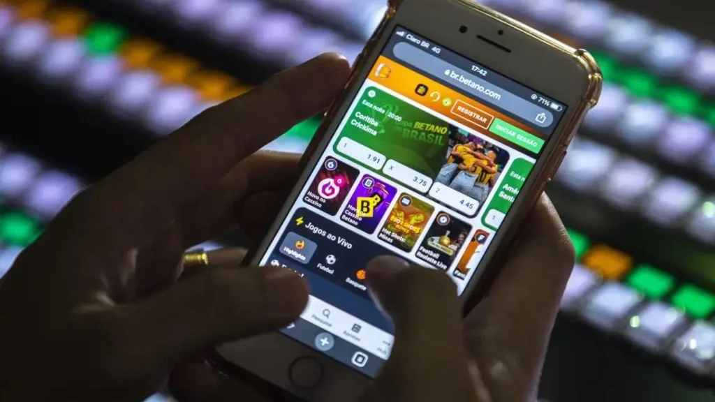 Pessoa segura celular com site de apostas aberto, em meio à MP que proíbe as bets
