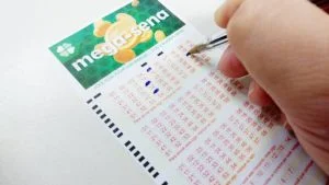 Mão com caneta marca números em volante da Mega-Sena; quanto rende o prêmio da Mega-Sena acumulado