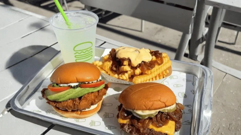 Lanches da Shake Shack em bandeja: hambúrguer, sanduíche de frango, batata e bebida; rede chega ao Brasil em 2027
