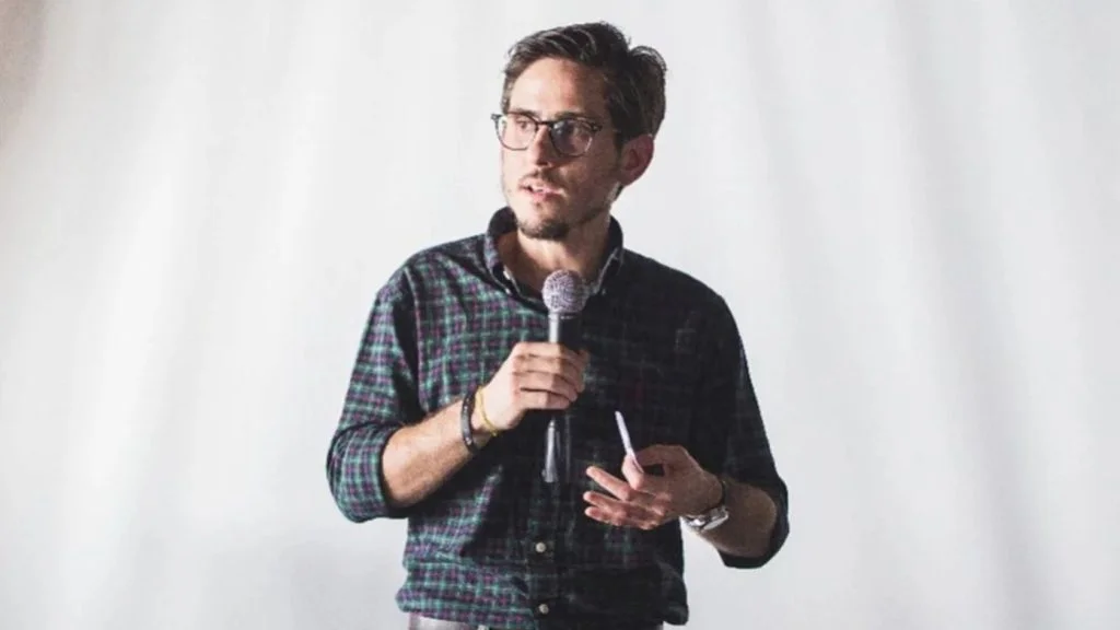 Fernando Cinelli, ex-presidente da Apex Partners, fala ao microfone de camisa xadrez e óculos