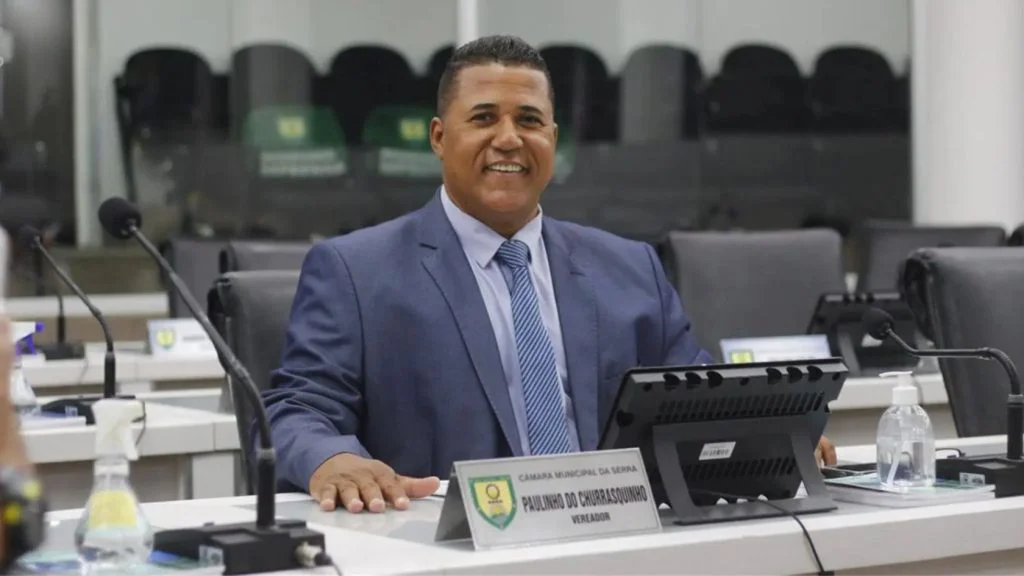 Vereador Paulinho do Churrasquinho, autor do projeto da Bíblia nas escolas da Serra, sorri sentado no plenário da Câmara