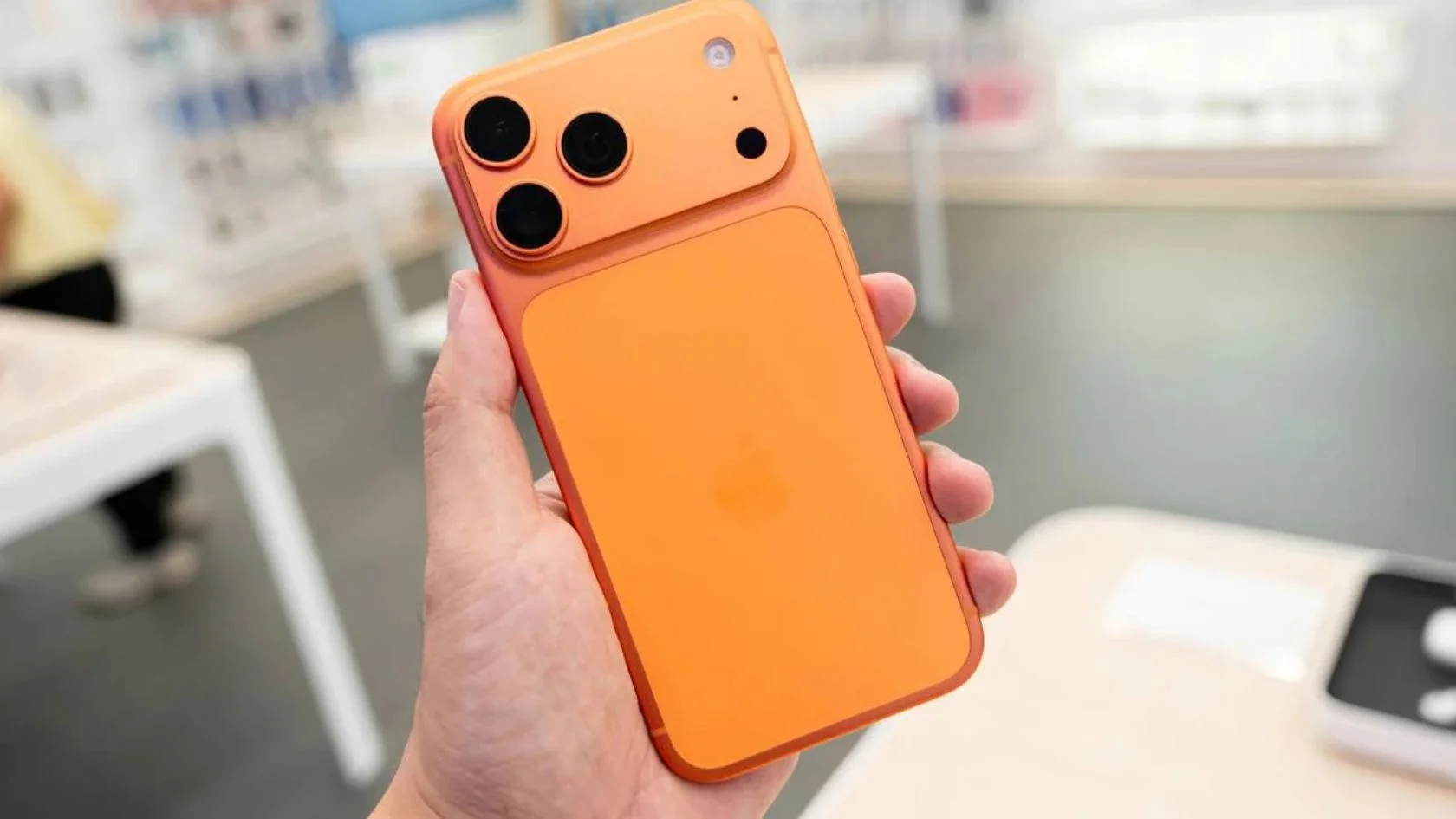 Mão segura iPhone da linha 17 Pro na cor laranja; modelos estão no leilão da Receita Federal