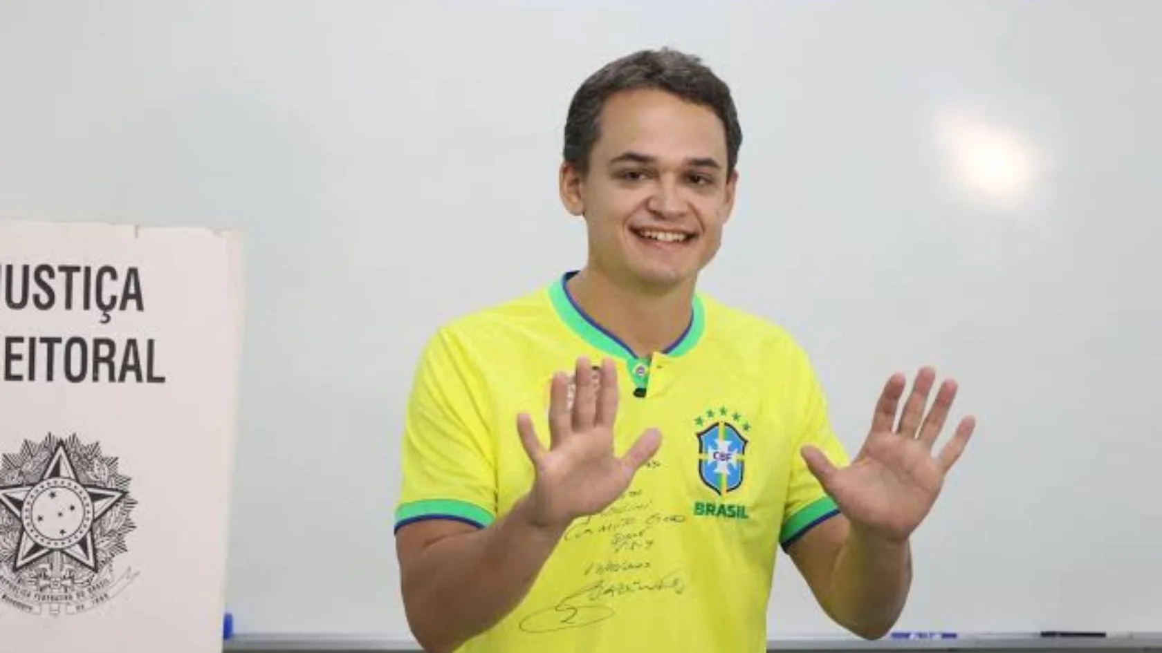 Lorenzo Pazolini, governador eleito do Espírito Santo, com camisa da seleção ao lado de cabine de votação
