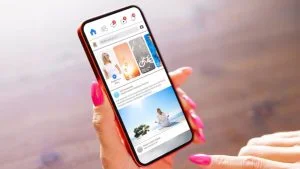 Mão segura celular com feed de rede social; Instagram testa vídeos de 90 minutos para competir com o YouTube