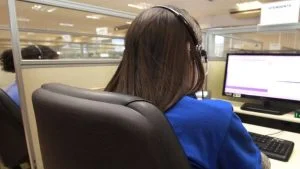 Atendente de costas com fone de ouvido em call center, imagem ilustrativa do caso da Vivo condenada pelo TST