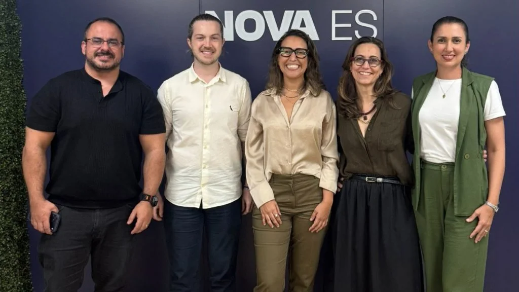 Representantes da Haier e da NOVA ES posam diante do painel da agência; Haier tem centro de distribuição na Serra