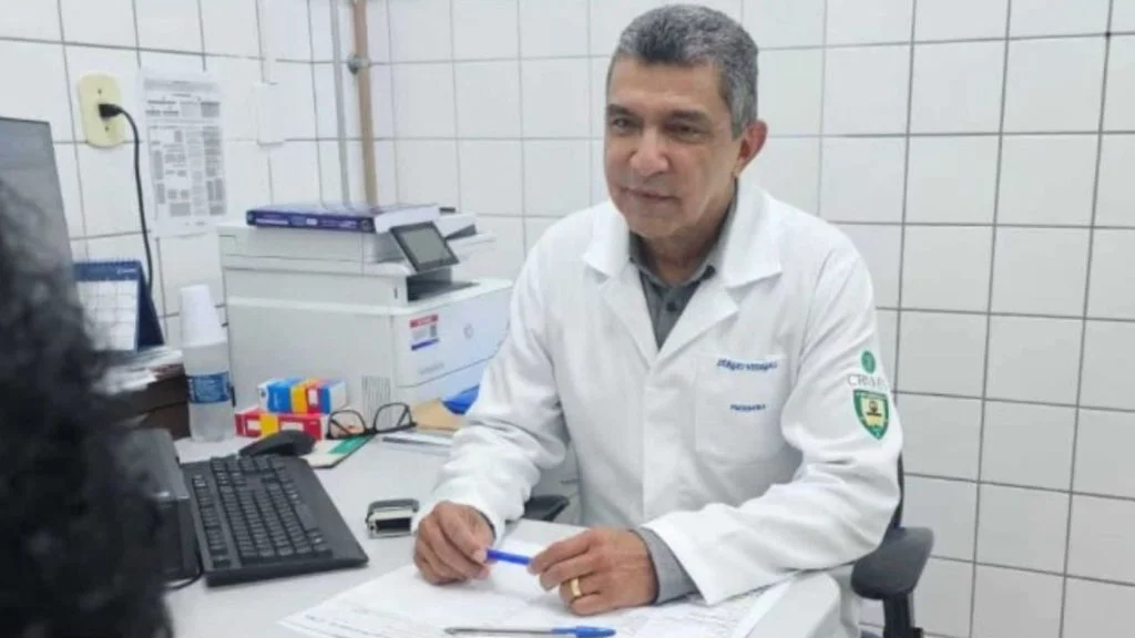 Sérgio Vidigal, de jaleco branco, atende paciente em consultório; ex-prefeito da Serra voltou a clinicar pelo SUS