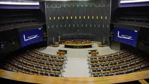 Resultado das Eleições 2026 para deputado federal no Rio de Janeiro O Rio de Janeiro elegeu 46 deputados federais para a Câmara dos Deputados nas Eleições 2026. Os parlamentares formarão a bancada do estado na Casa durante a legislatura que começa em 2027. A votação para deputado federal é realizada pelo sistema proporcional. Dessa forma, a definição das cadeiras não ocorre apenas pela comparação individual dos votos de todos os candidatos. A distribuição considera os votos válidos destinados aos partidos e federações e, posteriormente, os candidatos de cada legenda que ocuparão as vagas conquistadas. Por isso, a lista de eleitos não deve ser confundida com um ranking dos 46 candidatos mais votados individualmente. A composição final da bancada depende da distribuição proporcional das cadeiras prevista pela legislação eleitoral. Quantos deputados federais o Rio de Janeiro elege? O Rio de Janeiro tem direito a 46 cadeiras na Câmara dos Deputados. O número de vagas foi mantido para as Eleições 2026, assim como a distribuição das cadeiras entre os estados utilizada nas eleições anteriores. A Câmara dos Deputados é formada por representantes dos estados e do Distrito Federal, eleitos pelo sistema proporcional. Cada legislatura tem duração de quatro anos. Rio de Janeiro tem quantos eleitores em 2026? O Rio de Janeiro tem 12.857.000 eleitoras e eleitores aptos a votar nas Eleições 2026, segundo o Tribunal Regional Eleitoral do Rio de Janeiro (TRE-RJ). O número representa aumento de 0,23% em relação ao eleitorado registrado nas Eleições 2022. Do total de eleitores aptos em 2026, 10.421.768 possuem dados biométricos registrados, o equivalente a 81,06% do eleitorado fluminense. O estado realiza a votação em seus 92 municípios, dentro da estrutura eleitoral organizada pela Justiça Eleitoral fluminense. Quando os deputados federais eleitos pelo Rio de Janeiro assumem? Os deputados federais eleitos nas Eleições 2026 tomarão posse em 1º de fevereiro de 2027, data marcada pela Câmara dos Deputados para a posse dos parlamentares da 58ª Legislatura. O mandato de deputado federal tem duração de quatro anos. Qual é o salário de um deputado federal? O salário bruto mensal de um deputado federal é de R$ 46.366,19. O valor foi fixado pelo Decreto Legislativo nº 172/2022 e está em vigor desde 1º de fevereiro de 2025. A remuneração corresponde ao subsídio parlamentar. O pagamento considera, entre outros critérios, o comparecimento às sessões deliberativas do Plenário. Faltas não justificadas podem resultar em desconto. Além do subsídio, a Câmara mantém estruturas e recursos destinados ao exercício do mandato, como cota parlamentar, verba para funcionamento do gabinete, serviços de apoio e, conforme as regras da Casa, imóvel funcional ou auxílio-moradia. O que faz um deputado federal? O deputado federal atua na Câmara dos Deputados e participa do processo de elaboração das leis e da fiscalização do governo federal. Entre suas atribuições estão apresentar e votar projetos de lei, participar de comissões, discutir propostas de alteração da Constituição, fiscalizar atos do Poder Executivo e participar da análise do Orçamento da União. Os deputados também podem apresentar emendas parlamentares e atuar em comissões parlamentares de inquérito, além de exercer outras funções previstas pela Constituição e pelo Regimento Interno da Câmara. Onde trabalham os deputados federais? Embora sejam eleitos pelos estados que representam, os deputados federais têm como principal local de trabalho a Câmara dos Deputados, em Brasília. deputados federais rio de janeiro eleitos em 2026