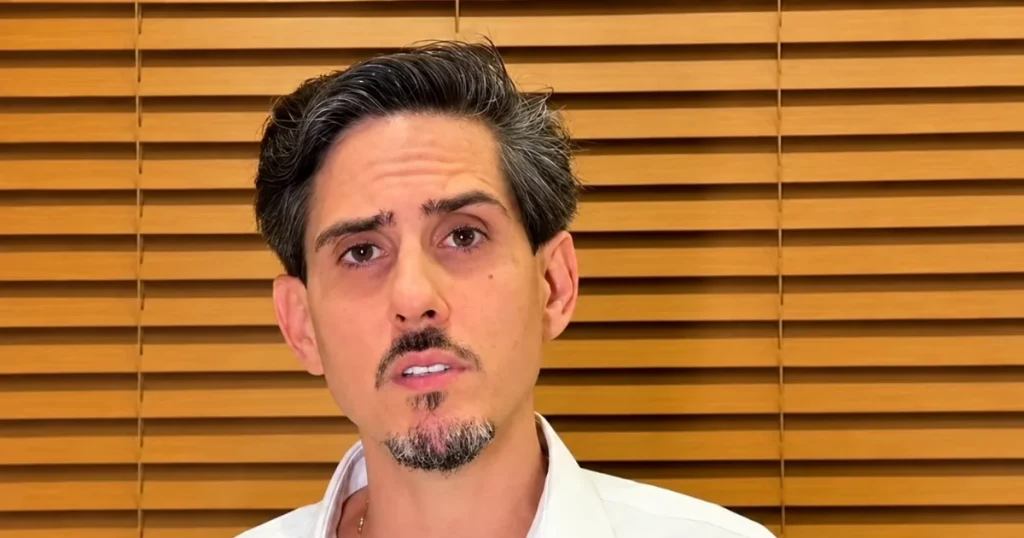 Fernando Cinelli, ex-presidente da Apex, fala à câmera de camisa branca, diante de persiana de madeira